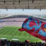 Trabzonspor fans wave a giant club flag inside a packed stadium during a Süper Lig match