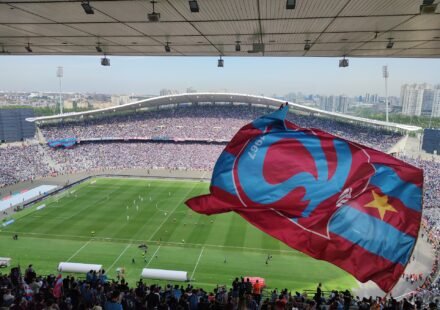 Trabzonspor fans wave a giant club flag inside a packed stadium during a Süper Lig match