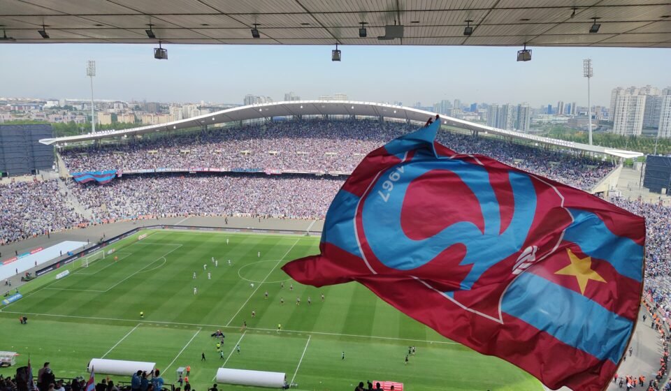 Trabzonspor fans wave a giant club flag inside a packed stadium during a Süper Lig match